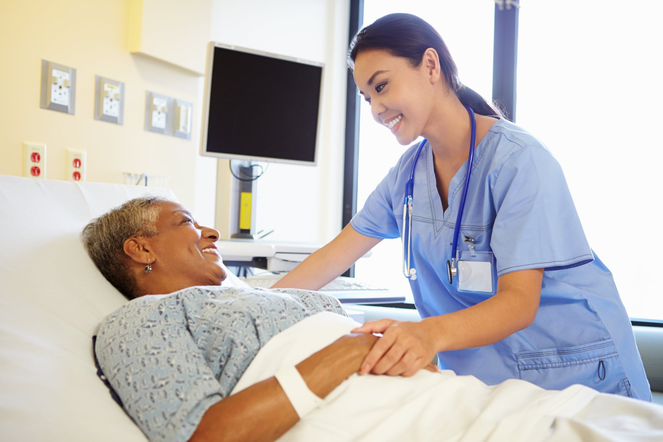 Smiling nurse holding female patient's hand